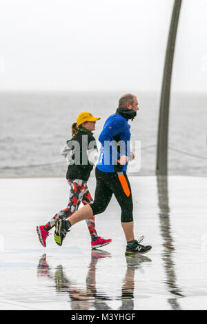 Coureurs À Blackpool, Lancashire. 13 févr. 2018. Royaume-Uni : froid, humide et rouillé, commencez la journée, tandis que deux joggers s'émiettent sur la promenade du front de mer. Normalement, un havre pour les visiteurs cette année de pause à mi-parcours est sans l'événement Showzam qui avait l'habitude de wow la foule dans les années précédentes. Les détours torrentiels rendent difficile pour les visiteurs et les touristes qui luttent avec les fortes rafales, les conditions bruteuses et venteuses. Les prévisions sont de continuer la persistance et souvent la forte pluie se déplaçant lentement vers l'est avec des vents forts Banque D'Images