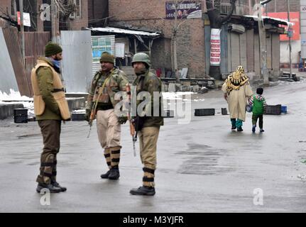 Srinagar, au Cachemire. Feb 13, 2018. Une femme du Cachemire et un enfant devant Kashmirn troopers paramilitaires qui montent la garde près de la rencontre en Kashmirn site Srinagar, Cachemire. Deux rebelles et un policier ont été tués dans une rencontre qui a duré plus de 28 heures à Srinagar. Les rebelles se cachaient depuis hier, au cours d'une demi-construction à Srinagar, après qu'ils ont attaqué une réserve centrale de Police (CRPF) camp à Karan Nagar, à Srinagar. Credit : Saqib Majeed/SOPA/ZUMA/Alamy Fil Live News Banque D'Images