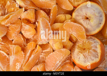De nouvelles matières premières pour le jus d'orange frais : un grand nombre de tranches d'orange et sur la droite deux demi-fruits épluchés. Banque D'Images
