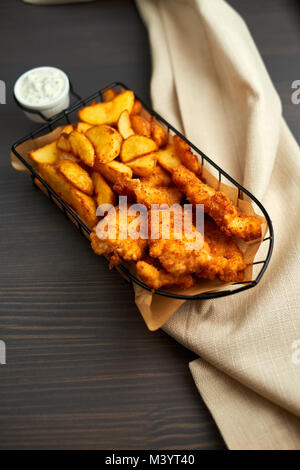 Nuggets et pommes de terre au four dans un beau panier avec de la sauce blanche Banque D'Images