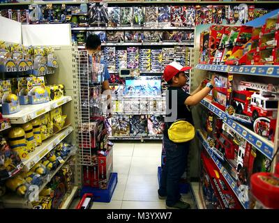 ANTIPOLO CITY, PHILIPPINES - le 28 janvier 2018 : un garçon joue avec les différents jouets sur l'affichage à un magasin de jouets. Banque D'Images