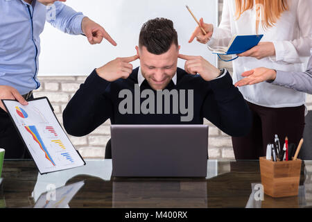 Les gens d'affaires en colère pointant collègue masculin lors du meeting in Office Banque D'Images