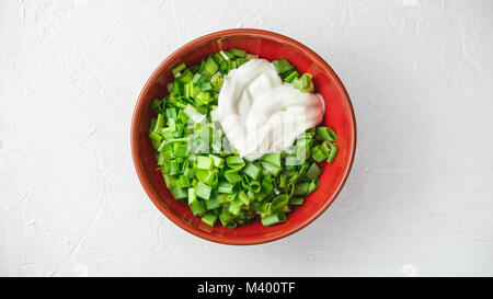 Tranchés, coupés du printemps, salade, Oignons ou échalotes vertes avec de la crème dans un bol sur le fond texturé Blanc Banque D'Images