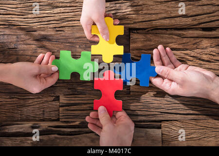 View Of Hands Holding Puzzle coloré sur un bureau en bois Banque D'Images