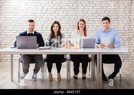 Portrait Of Happy Businesspeople Holding Appareils électroniques Au travail Banque D'Images