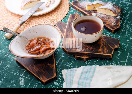 L'heure du thé. Confiture d'abricot, Tarte au fromage cottage et une tasse de thé sur les planches de bois. Des formules mathématiques sur fond nappe Banque D'Images