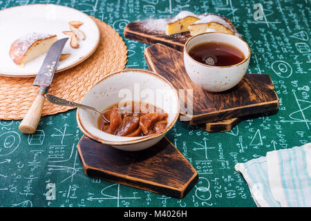 L'heure du thé. Confiture d'abricot, Tarte au fromage cottage et une tasse de thé sur les planches de bois. Des formules mathématiques sur fond nappe Banque D'Images