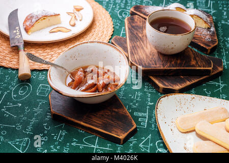 L'heure du thé. Confiture d'abricot, Tarte au fromage cottage et une tasse de thé sur les planches de bois. Des formules mathématiques sur fond nappe Banque D'Images