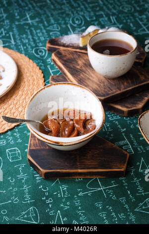 L'heure du thé. Confiture d'abricot, Tarte au fromage cottage et une tasse de thé sur les planches de bois. Des formules mathématiques sur fond nappe Banque D'Images