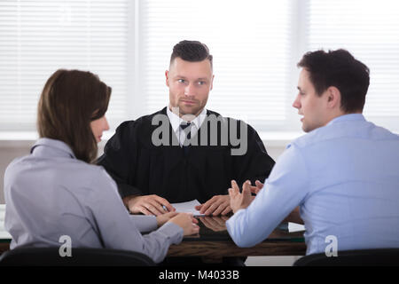 Jeune couple soutenant les uns avec les autres en face de juge au Tribunal Banque D'Images