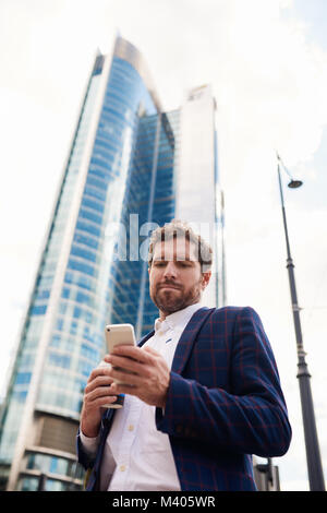 Young businessman standing dans la ville la lecture de messages texte Banque D'Images