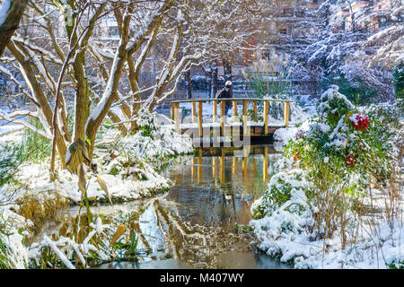 Petite rivière avec un mini-pont dans le parc, piscine en plein air à Paris, en France, au cours de la neige en hiver. Prise le matin avec le lever du soleil la lumière. Concept Smart Banque D'Images