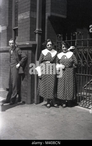 Années 1920, historiques, deux dames, soeurs ?, le port correspondant à la longueur de la cheville robes à motifs à pois blanc avec encolure et aux manches, à l'extérieur par une entrée fermée, England, UK. Ces robes étaient un article de mode féminine populaire en ce moment et souvent portés dans l'après-midi et semi-formelle d'usure. Banque D'Images