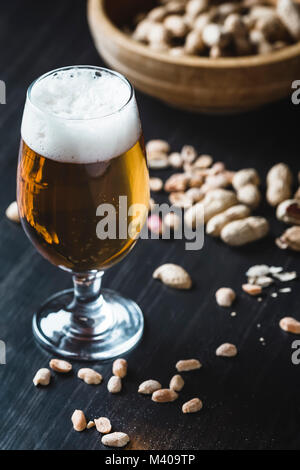 Verre de bière et d'arachides sur le fond en bois foncé Banque D'Images