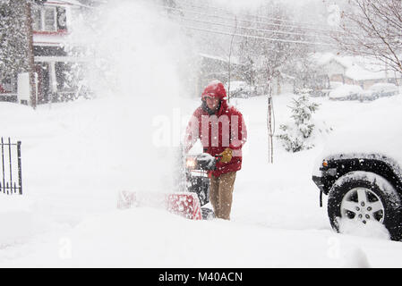 Homme qui court une souffleuse à neige poudrerie d'une entrée dans une tempête dans les Adirondacks, NY USA Banque D'Images