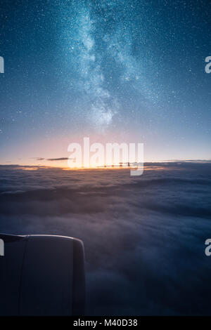 Belle vue sur le lever du soleil au-dessus des nuages en vu de la fenêtre de l'avion à turbine d'avion et Milky Way sur sky Banque D'Images