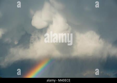 Un arc-en-ciel ci-dessous sombre de nuages de pluie au printemps Banque D'Images