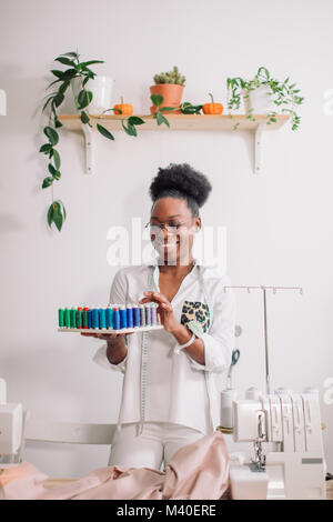 Couturière africaine holding bobines avec filetage Banque D'Images