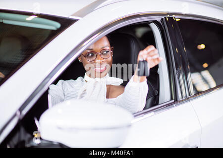 Femme africaine avec sa nouvelle voiture montrant les principaux Banque D'Images