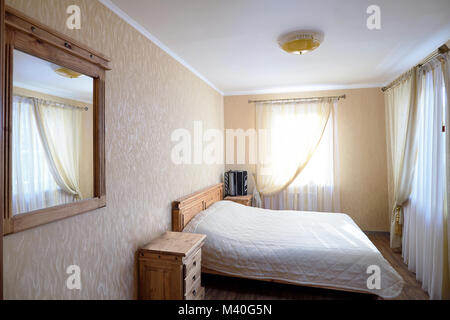 Intérieur d'une chambre d'une maison rurale avec un bayan sur une table de nuit dans des tons pastel Banque D'Images