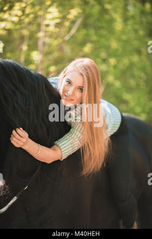 Jeune fille aux longs cheveux couché sur le cou du cheval Banque D'Images