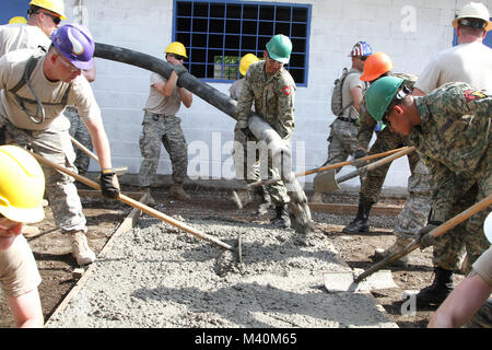 Les troupes de la 891e bataillon du génie de Iola, Kansas, et ingénieurs d'Battelion Enginero salvadorien de centrale Comando de Ingenieros de la Fuerza Armada, couler le béton dans des formulaires pour faire un trottoir dans une école projet de construction à sitio del Niño le 27 mai pendant au-delà de l'horizon 2015. BTH15 est un programme conjoint de l'aide humanitaire et l'exercice de l'ingénierie municipale parrainé par U.S. Southern Command et le gouvernement d'El Salvador pour montrer mon soutien pour le pays d'El Salvador. (U.S. Photo de l'armée par le Sgt. Jeff Daniel) 150527-A-RJ par ussouthcom477-0025 Banque D'Images