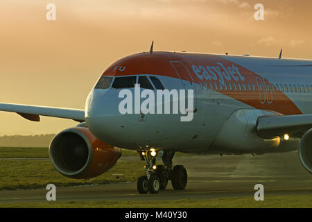 Un avion de passagers d'Easyjet en roulage sur une piste pour décoller à l'aéroport John Lennon de Liverpool au crépuscule. Banque D'Images