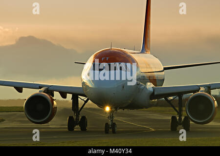 Un avion de passagers d'Easyjet en roulage sur une piste pour décoller à l'aéroport John Lennon de Liverpool au crépuscule. Banque D'Images