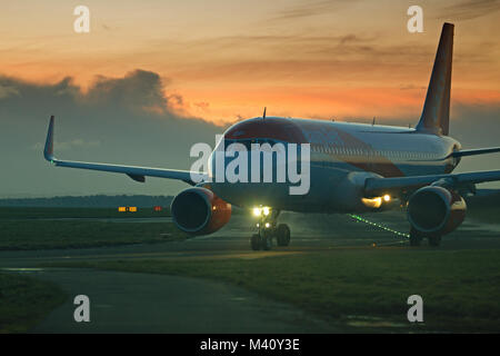 Un avion de passagers d'Easyjet en roulage sur une piste pour décoller à l'aéroport John Lennon de Liverpool au crépuscule. Banque D'Images