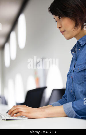 Asian businesswoman la saisie sur un clavier Banque D'Images