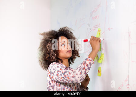 Élève écrit sur un tableau blanc Banque D'Images