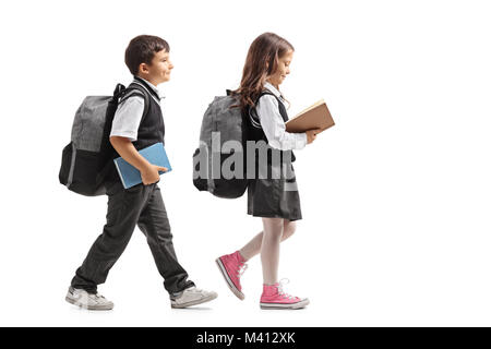 Profil de pleine longueur tourné un écolier et d'écolière avec des sacs et des livres marcher isolé sur fond blanc Banque D'Images