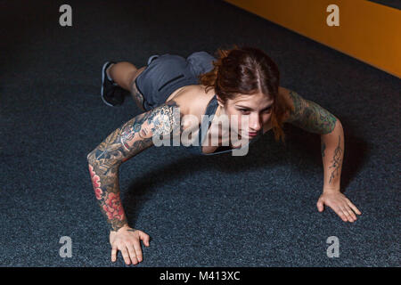 La jeune fille est en train de faire des exercices dans la salle de sport. La formation de remise en forme dans la salle de sport. Banque D'Images