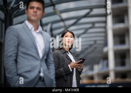 Businesswoman waiting pour former sur la plate-forme avec le smartphone dans la main Banque D'Images