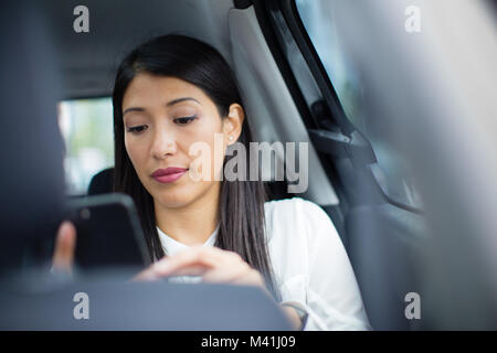 Businesswoman in taxi cab using smartphone Banque D'Images