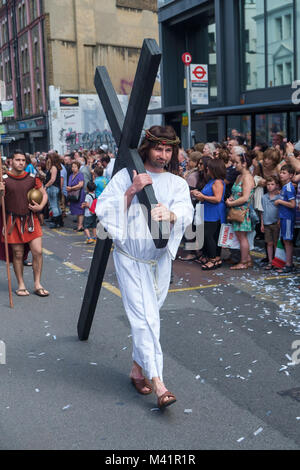 Le Christ porte une croix noire suivi d'un soldat romain dans la procession à la fête de Notre-Dame du Mont Carmel à l'Église italienne à Clerkenwell. Banque D'Images