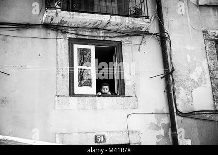 Un garçon à la fenêtre à Lisbonne, Portugal. Banque D'Images