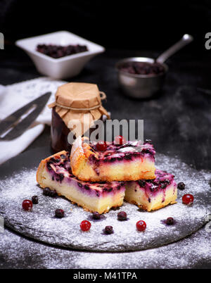 Les secteurs de fromage cottage et de bleuets sur fond noir saupoudré de sucre en poudre, Close up Banque D'Images