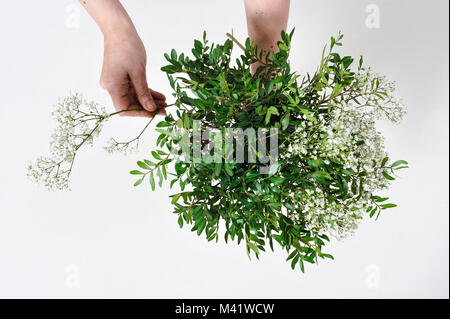 Bois de fleurs d'être organisés pour une occasion spéciale comme la Saint-Valentin. Coupe femme les tiges des fleurs après les arrangeant. Banque D'Images