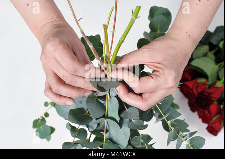 Bois de fleurs d'être organisés pour une occasion spéciale comme la Saint-Valentin. Coupe femme les tiges des fleurs après les arrangeant. Banque D'Images