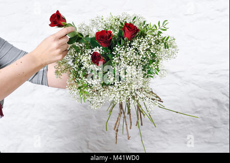 Bois de fleurs d'être organisés pour une occasion spéciale comme la Saint-Valentin. Coupe femme les tiges des fleurs après les arrangeant. Banque D'Images