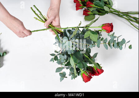 Bois de fleurs d'être organisés pour une occasion spéciale comme la Saint-Valentin. Coupe femme les tiges des fleurs après les arrangeant. Banque D'Images