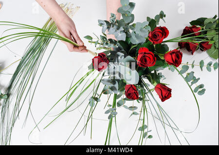 Bois de fleurs d'être organisés pour une occasion spéciale comme la Saint-Valentin. Coupe femme les tiges des fleurs après les arrangeant. Banque D'Images