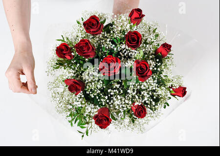 Bois de fleurs d'être organisés pour une occasion spéciale comme la Saint-Valentin. Coupe femme les tiges des fleurs après les arrangeant. Banque D'Images