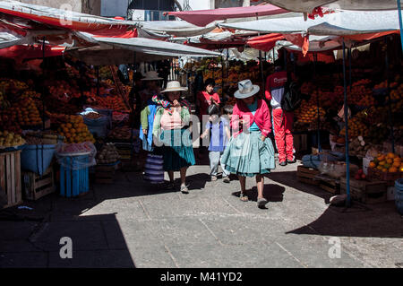 Les femmes portant des chapeaux et des vêtements traditionnels en se promenant dans un marché avec leurs enfants en Sucre, Bolivie Banque D'Images