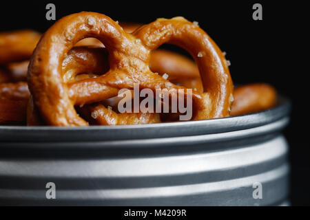 Bretzels croustillants apéritif dans un pot en métal sur un tableau noir. Lumière mystique style. Banque D'Images