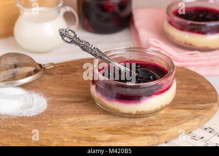 Cheesecake dans un bocal en verre avec les cookies et les baies. Banque D'Images