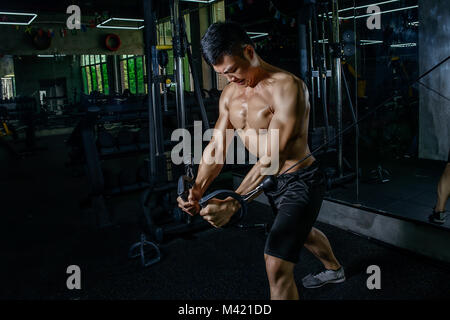 Sports beau jeune homme asiatique faisant des exercices sur sa poitrine à la hauteur de la liaison dans la salle de sport. L'homme sportif cool avec de grands muscles. Banque D'Images