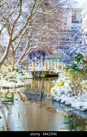 Petite rivière avec un mini-pont dans le parc, piscine en plein air à Paris, en France, au cours de la neige en hiver. Prise le matin avec le lever du soleil la lumière. Concept Smart Banque D'Images