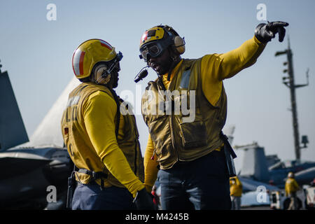 180115-N-VN584-1728 Golfe Arabique (jan. 15, 2018) l'Aviation maître de Manœuvre (manutention) 1re classe Edmond Scott, à gauche, et l'Aviation maître de Manœuvre (manutention) 1re classe Paul Hall discuter des opérations de vol sur le pont du porte-avions USS Theodore Roosevelt (CVN 71). Theodore Roosevelt et son groupe aéronaval sont déployés dans le domaine de la 5e flotte américaine des opérations à l'appui des opérations de sécurité maritime pour rassurer les alliés et les partenaires et de préserver la liberté de navigation et la libre circulation du commerce dans la région. (U.S. Photo par marine Spécialiste de la communication de masse de la classe de 3ème Banque D'Images